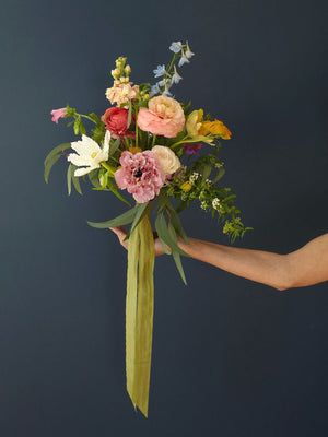 a woman holding a bouquet of flowers in her hand