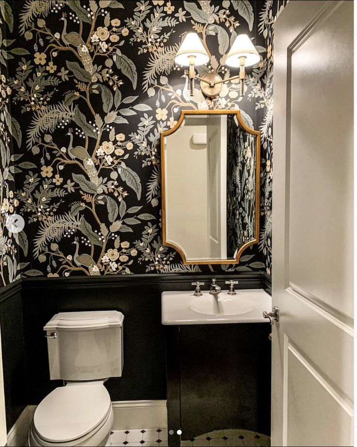 a bathroom with black and white wallpaper has a mirror above the toilet