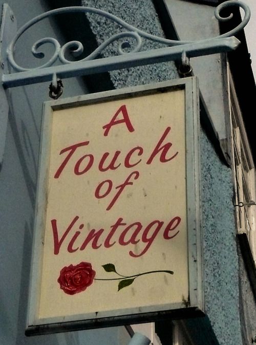 a touch of vintage sign hanging from the side of a building