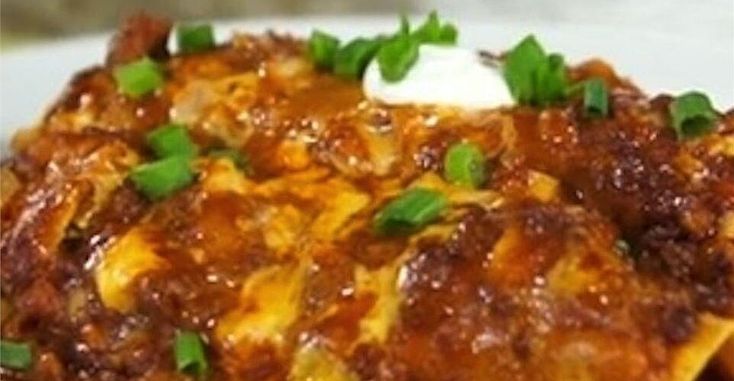 a white plate topped with lasagna covered in sauce and cheese, garnished with green onions