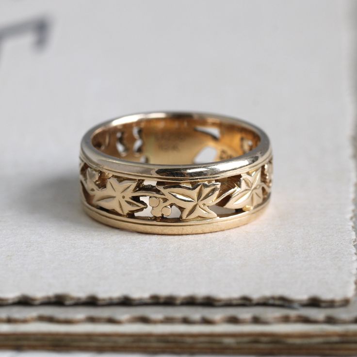 "A beautifully detailed vintage band crafted in solid 18k yellow gold showcasing the centuries-old language of flowers with it's articulated ivy motif. The ivy leaf was used to represent the ideals of fidelity, marriage, friendship and affection; it's meaning is underlined by the eternity style of the ring, unbroken and endless. Originally meant as a wedding ring, it would be perfect worn in a stack with other interesting bands or on its own as a solo statement. Measuring approximately 6.88 mm w Vintage Yellow Gold Flower Ring For Wedding, Vintage Yellow Gold Flower Wedding Ring, Classic 14k Stamped Yellow Gold Flower Ring, Heirloom Yellow Gold Flower Ring With Intricate Design, Heirloom Gold Flower Ring, Art Nouveau Engraved Yellow Gold Ring, Art Nouveau Gold Engraved Rings, Art Nouveau Style Gold Engraved Rings, Art Nouveau Style Engraved Gold Rings