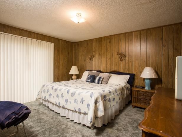 a bed sitting in a bedroom next to two lamps and a wooden wall behind it