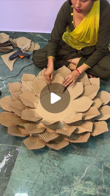 a woman sitting on the floor making a flower out of cardboard