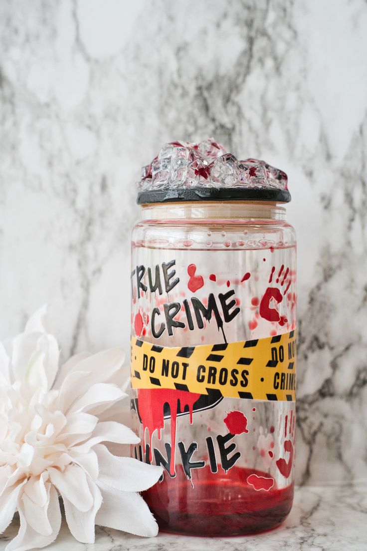 a white flower sitting next to a glass jar with some writing on it and a sticker