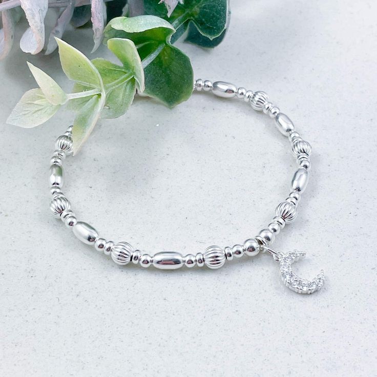 This beautiful sterling silver celestial bracelet that embodies both beauty and symbolism, features a stunning, Cubic Zirconia crescent moon charm that represents intuition and feminine energy  This bracelet allows you to carry the symbolism and energy of the moon with you wherever you go. Whether you're seeking a meaningful gift for a loved one or a personal talisman for yourself, this enchanting accessory serves as a timeless expression of cosmic connection and spiritual significance  The eclectic mix of high-quality sterling silver beads are stung onto strong, professional grade jewellers' elastic, meaning there are no fiddly clasps to deal with, simply roll the bracelet over your hand and onto your wrist Sterling silver is a precious metal known for its durability, luster and resistanc Silver Beaded Bracelets With Moon Charm As Gift, Sterling Silver Bracelet With Moon Charm, Sterling Silver Bracelets With Moon Charm, Elegant Sterling Silver Bracelets With Moon Charm, Celestial Sterling Silver Bracelets, Sterling Silver Celestial Bracelet With Moon Charm, Sterling Silver Moon Charm Bracelet, Sterling Silver Moon Phase Bracelet As Gift, Sterling Silver Moon Phase Bracelet For Gift