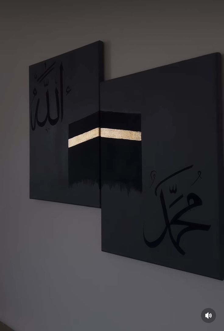 two black paintings hanging on the wall with gold trimmings and arabic calligraphy