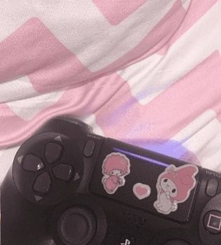 a video game controller sitting on top of a pink and white striped blanket with cartoon characters