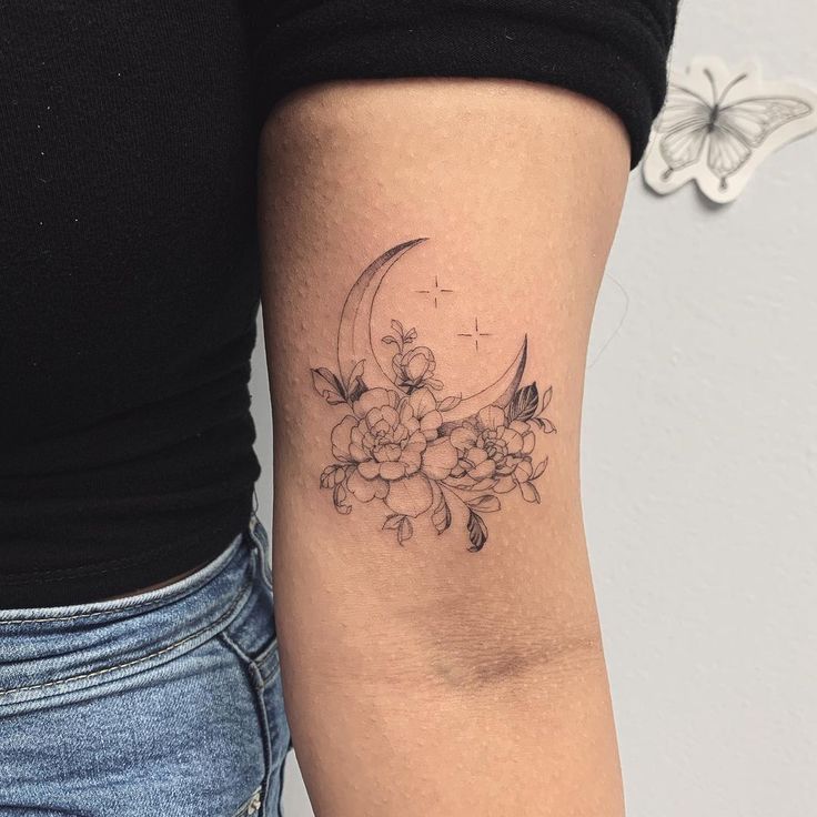 a woman's arm with flowers and a crescent tattoo on the left side of her arm