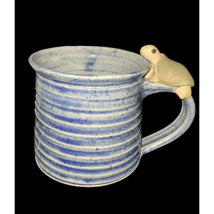 a blue and white mug with a bird on it's handle, against a black background