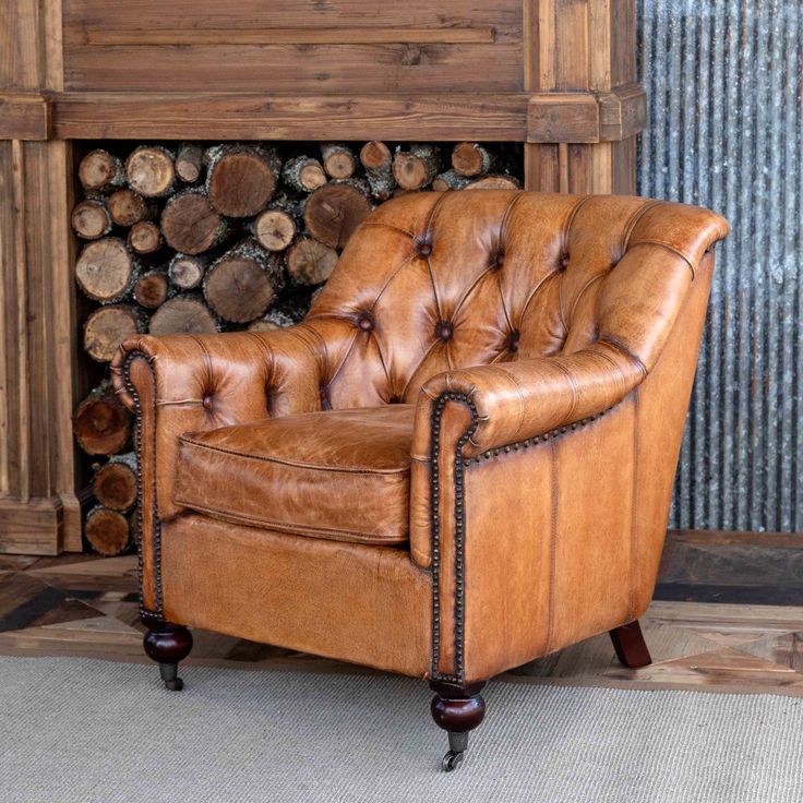 a brown leather chair sitting in front of a fire place with logs stacked on top of it