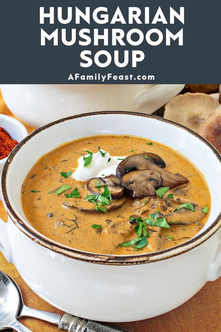 a white bowl filled with mushroom soup on top of a wooden table next to silverware