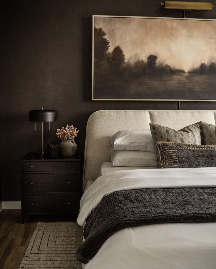 a bed with white sheets and pillows in a bedroom next to a painting on the wall