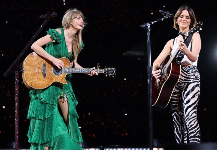 two women are playing guitars and singing on stage