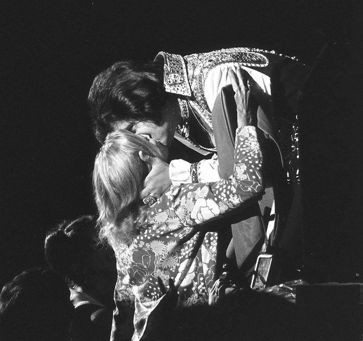 a woman holding a child in her arms while standing next to a man on stage