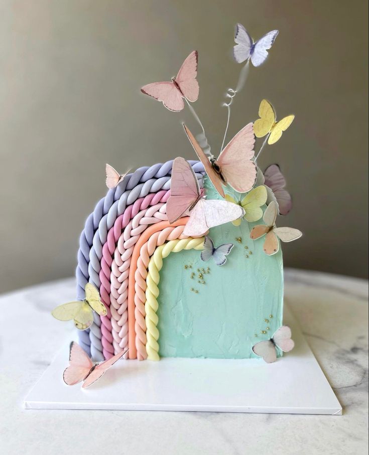 a cake decorated with butterflies on top of a table