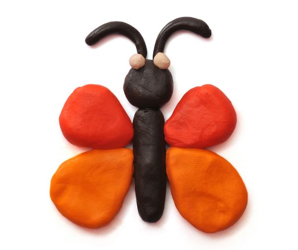 an orange and black butterfly sitting on top of a white surface