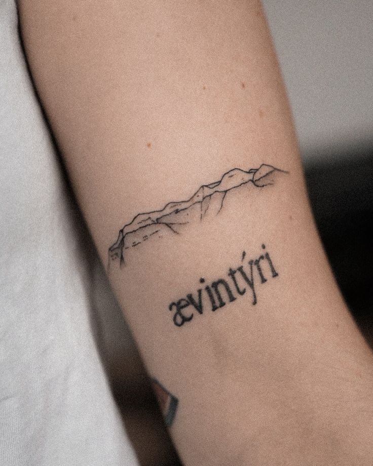 a woman with a tattoo on her arm that says avnvyri in black ink