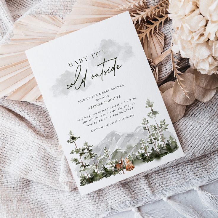 an image of a wedding card on top of a bed with flowers and feathers around it