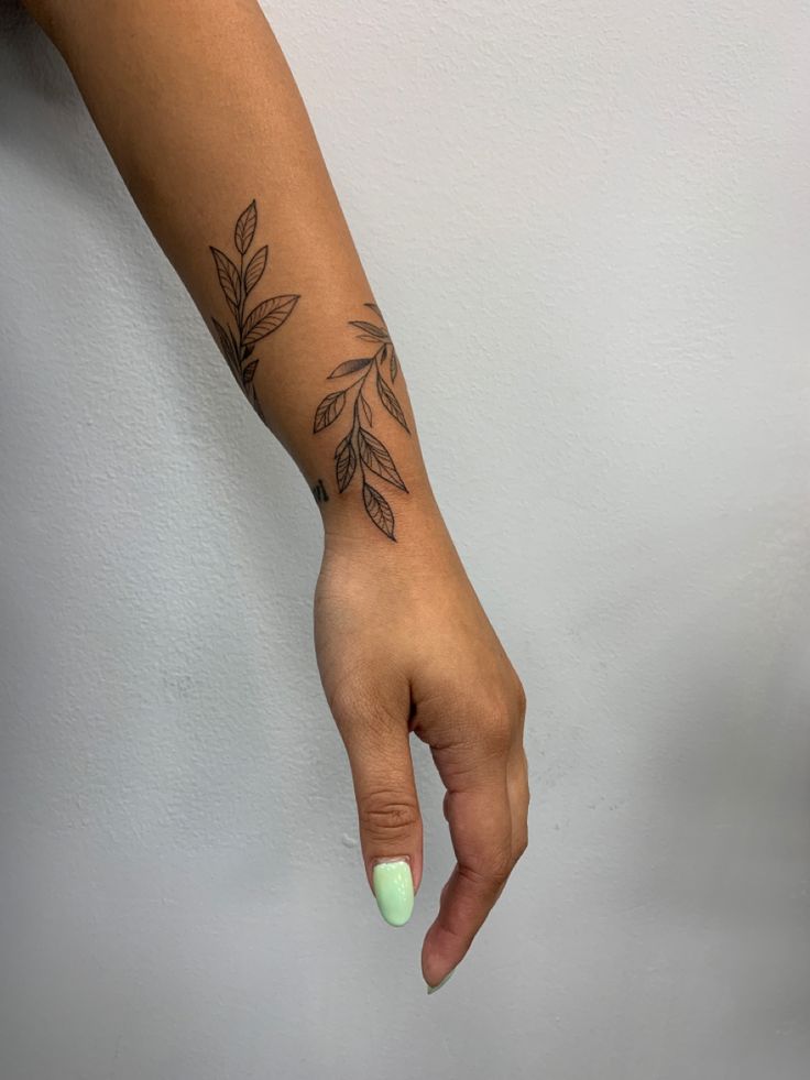 a woman's hand with a small tattoo on her left arm and green nail polish