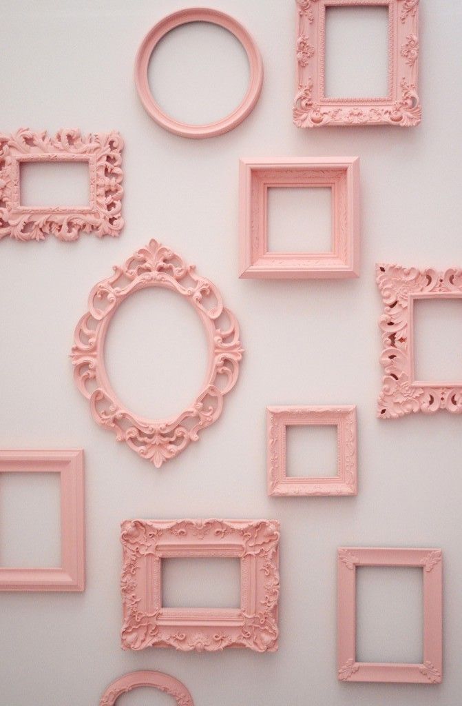 pink frames are arranged on the wall in different shapes and sizes, including one with an oval