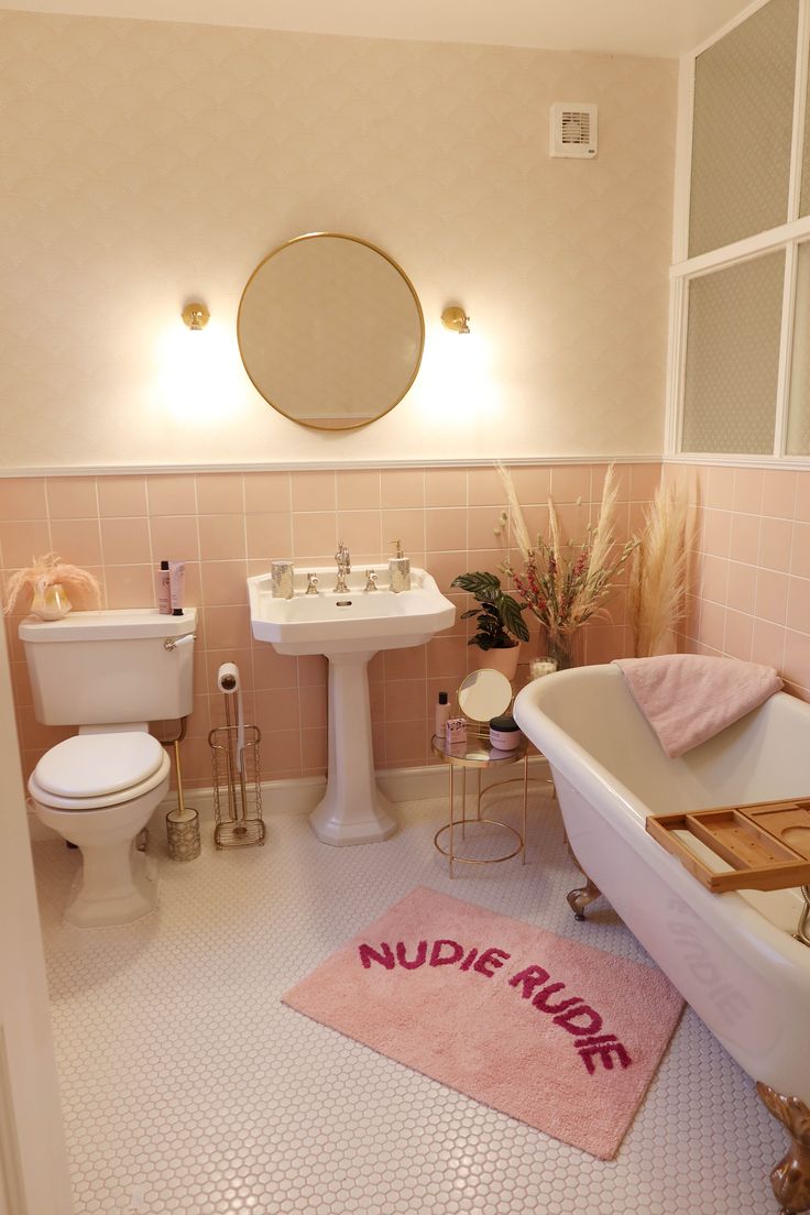 a bathroom with pink walls and flooring has a bathtub, sink, toilet and mirror