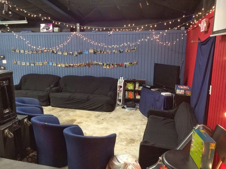 a living room filled with black furniture and lots of lights hanging from the ceiling above