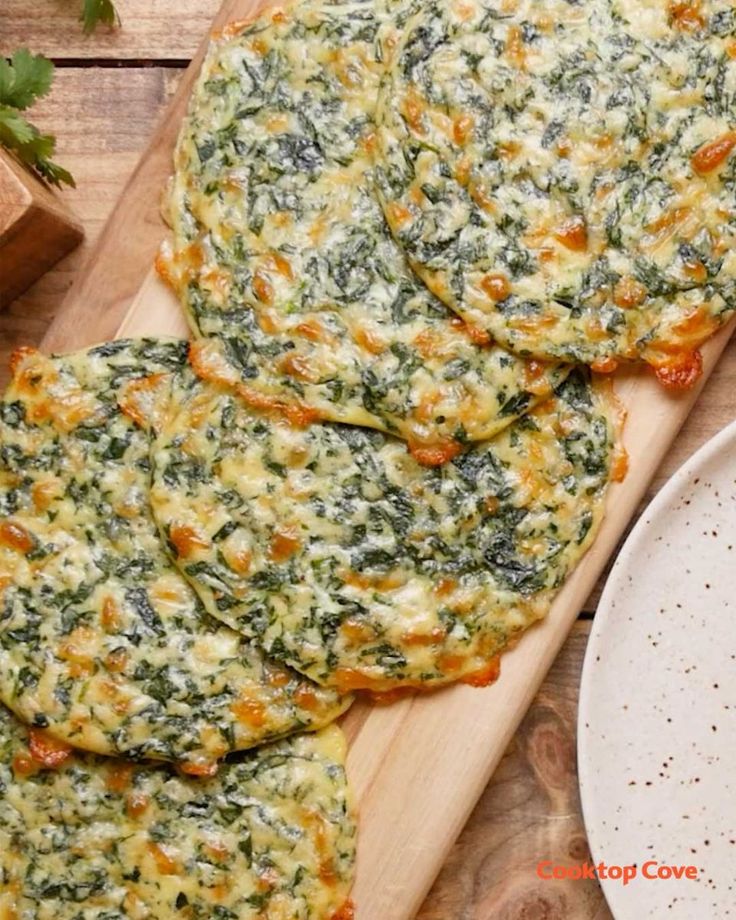 spinach and cheese fritters on a wooden cutting board next to a plate