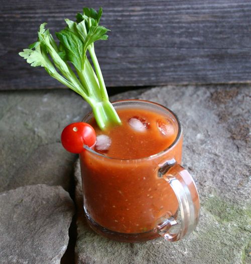 a glass filled with liquid and garnish sitting on top of a rock