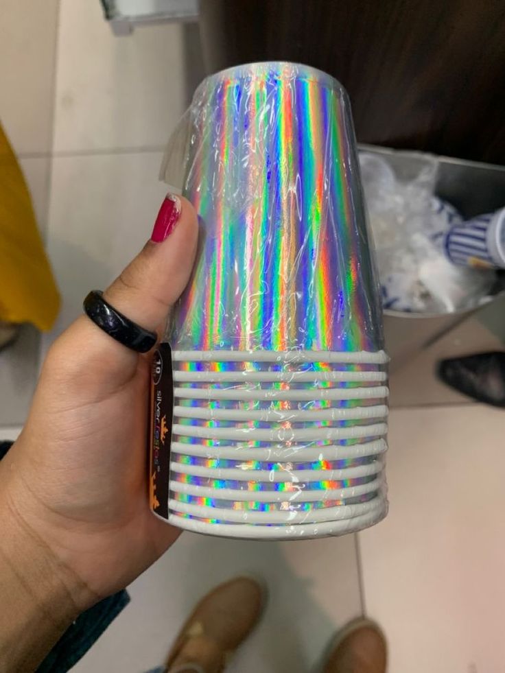 a person holding up a cup with holographics on it