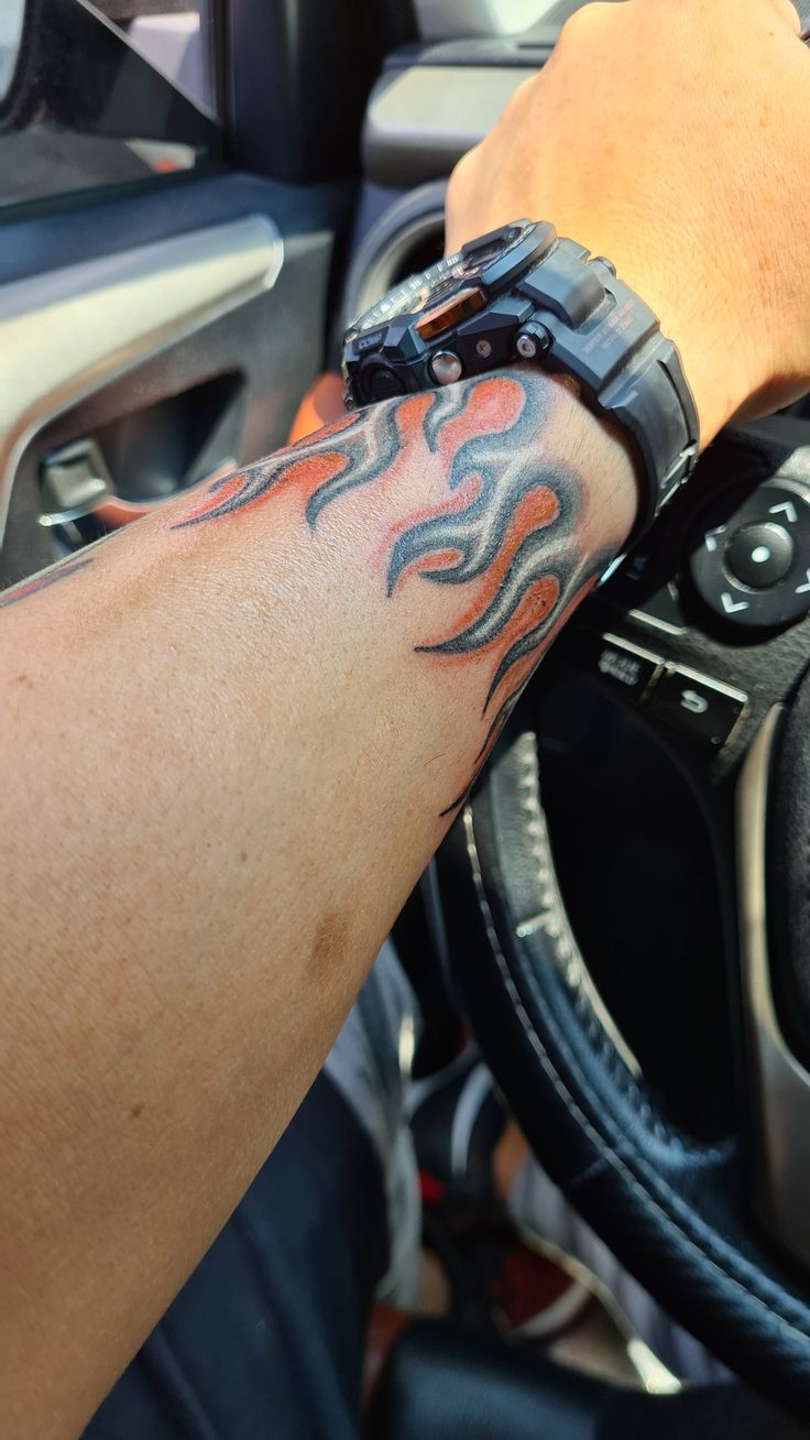 a man with a tattoo on his arm is driving a car and holding the steering wheel