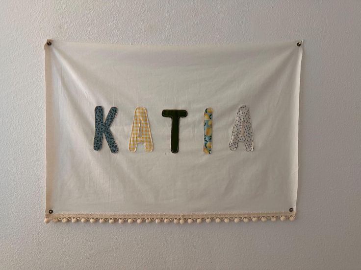 the name kate is made out of letters on a white banner with tassels