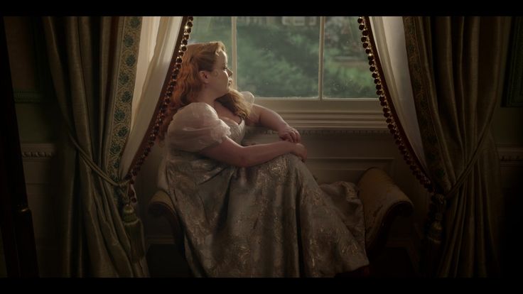 a woman sitting on a chair in front of a window