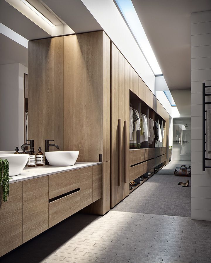 a large bathroom with two sinks and wooden cabinetry on the wall, along with hanging towels