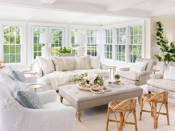 a living room filled with white furniture and lots of windows in it's walls