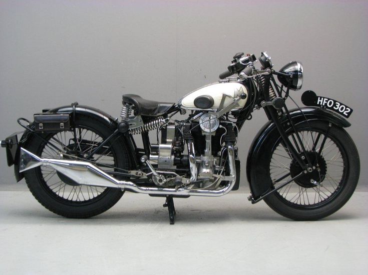 an old model motorcycle is parked on the floor in front of a gray wall,