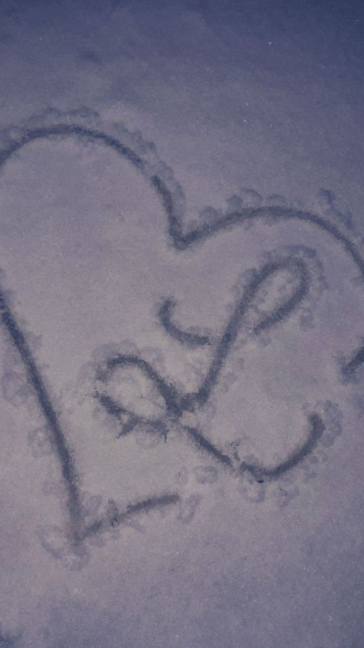 a heart drawn in the snow with two hands