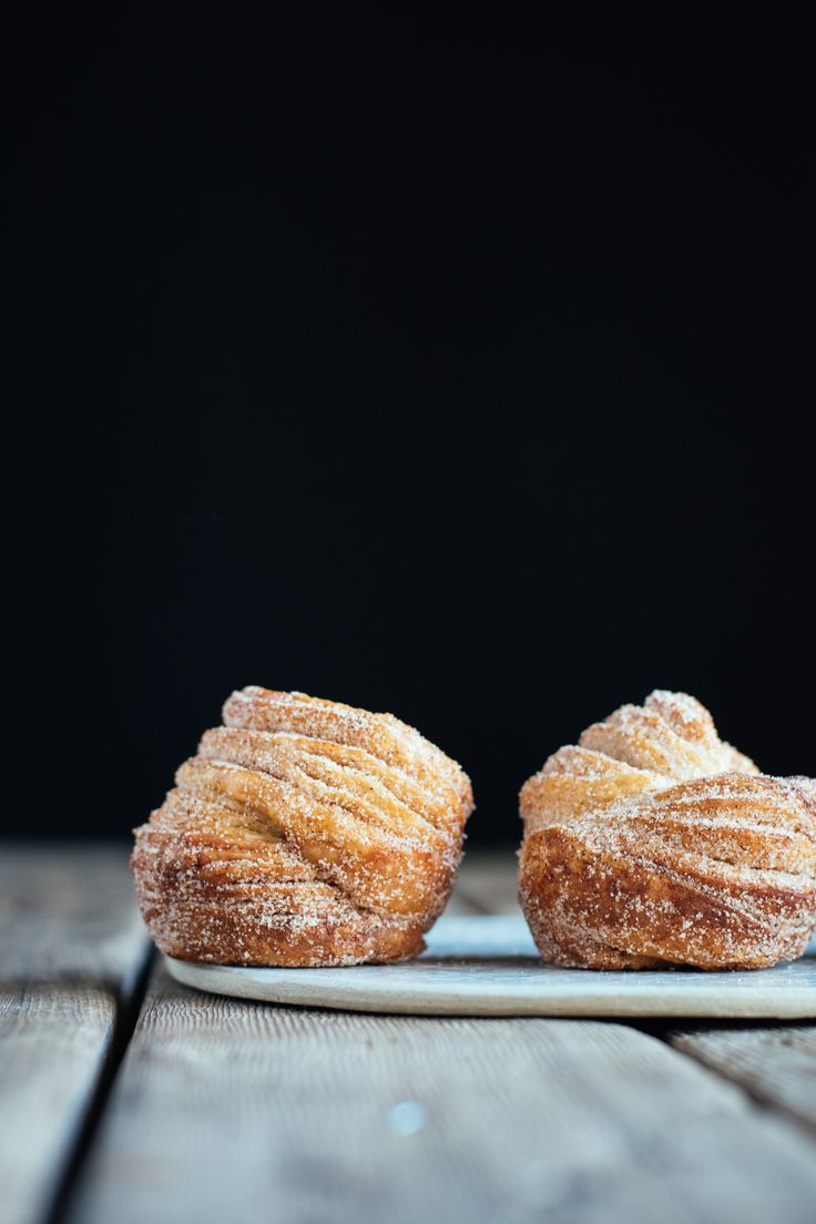 two pastries sitting on top of a plate covered in powdered sugar and sprinkled with icing