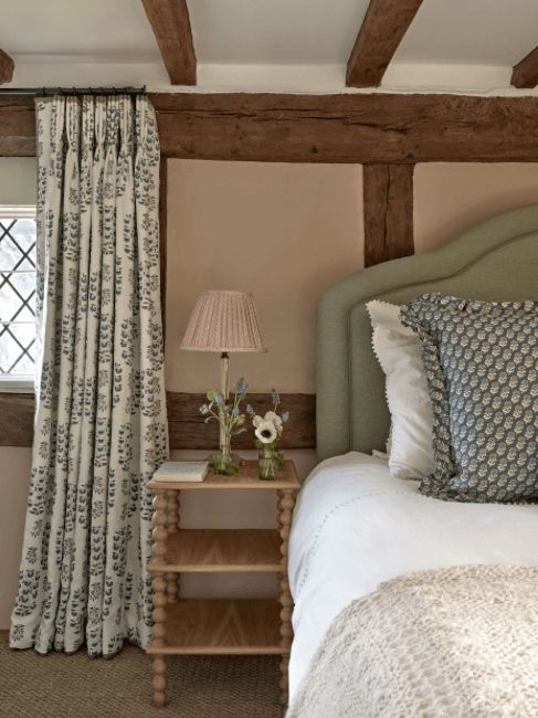 a bed sitting next to a window in a room with wooden beams on the ceiling