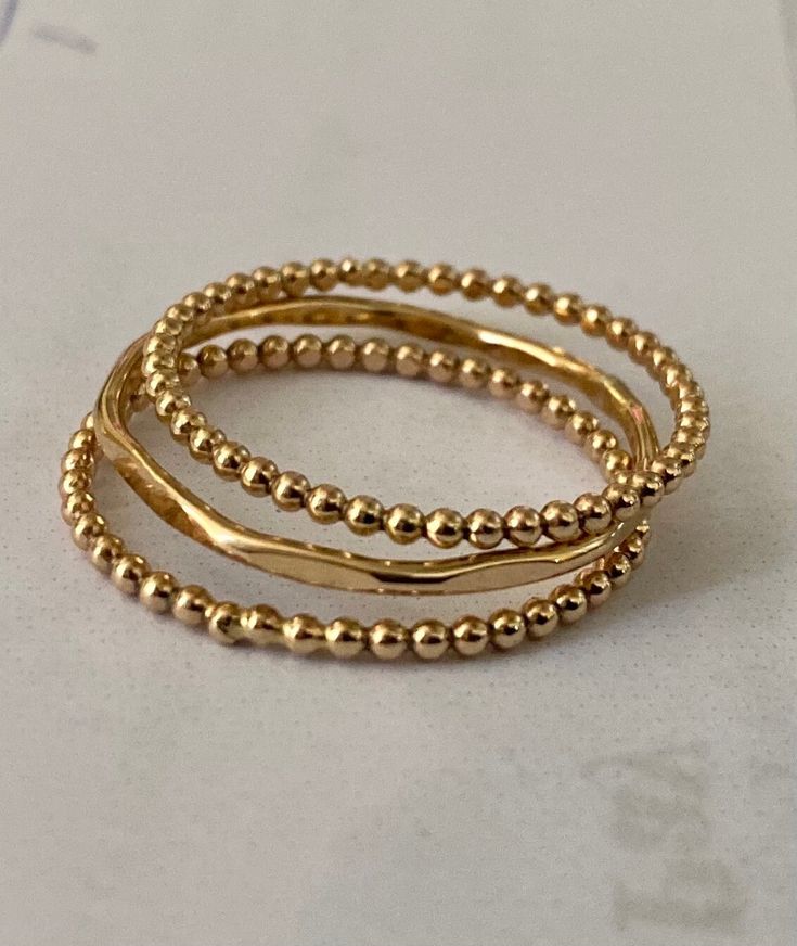 Gold filled ring bands that are perfect for wearing as stackable rings as shown in photos or wearing alone.  The ring bands are 3 different designs.  2 bead wire bands and 1 hammered textured band.  They will soon become your daily wear ring bands.  They are comfortable, so much that you forget your wearing them.  I wear a set everyday!  SIZE  The 3 rings are made of 14 gauge wire, 14Kgold filled.  SHIPPING  The shipping on these rings will take approximately 2-6 business days using USPS first class mail service. It will arrive in a gift box and bubble wrap envelope ready for gift giving, for any friend, loved one or yourself! Dainty Stacked Rings As A Gift, Adjustable Stacked Gold Midi Rings, Dainty Stacked Round Jewelry, Adjustable Stackable Midi Promise Rings, Dainty Stackable Jewelry, Dainty Inelastic Stackable Jewelry, Stacked Round Beads Jewelry As Gift, Stacked Round Beads Jewelry For Gift, Stacked Round Beads Jewelry Gift