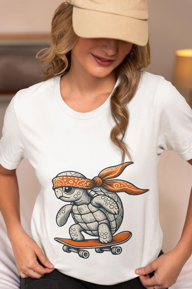 This unisex T-Shirt features a unique hand-drawn design of a cool turtle riding a skateboard and sporting an orange bandana. Ideal for skaters, turtle enthusiasts, and anyone who loves fun and quirky graphics, this tee combines style and personality. Made from high-quality materials, it offers both comfort and durability. Wear it to showcase your love for skateboarding or as a standout piece in your casual wardrobe. Perfect for gifting to friends and family who appreciate unique and artistic designs. We utilize the authentic Bella Canvas 3001 brand, renowned for its UNISEX design, making it one of the most sought-after shirts in the market. Prior to placing an order, kindly refer to our size chart. It can be located in both the listing's images and description. This cozy T-shirt serves as Casual T-shirt With Custom Artwork, Casual White T-shirt With Custom Artwork, Casual Surfing T-shirt With Custom Print, Casual Cotton Sublimation T-shirt With Cartoon Print, Casual Crew Neck Sublimation Design With Custom Artwork, Casual Crew Neck With Cartoon Sublimation Design, Casual Crew Neck Sublimation Shirt With Cartoon Print, Turtle On Skateboard, Orange Bandana