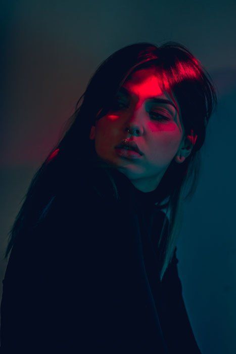 a woman with dark hair and red light on her eyes is looking at the camera