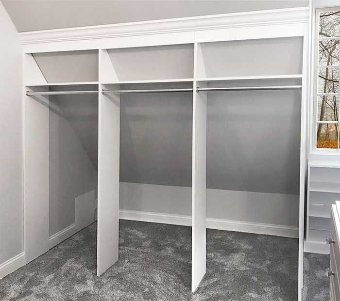 an empty walk in closet with white walls and carpeted flooring on the ground