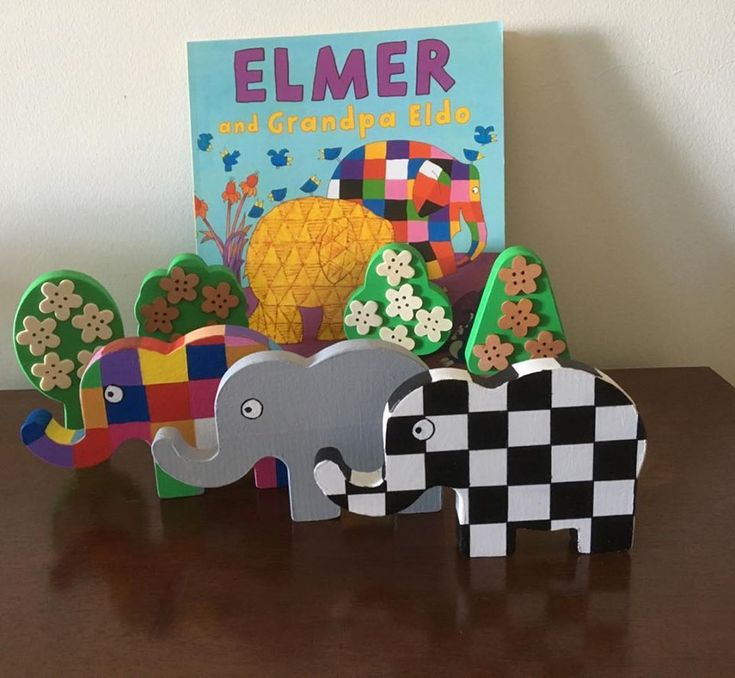 an elephant, giraffe and zebra are on the table next to a book