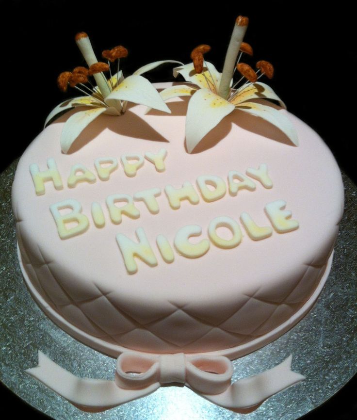 a pink birthday cake with white flowers and the words happy birthday nicole on it