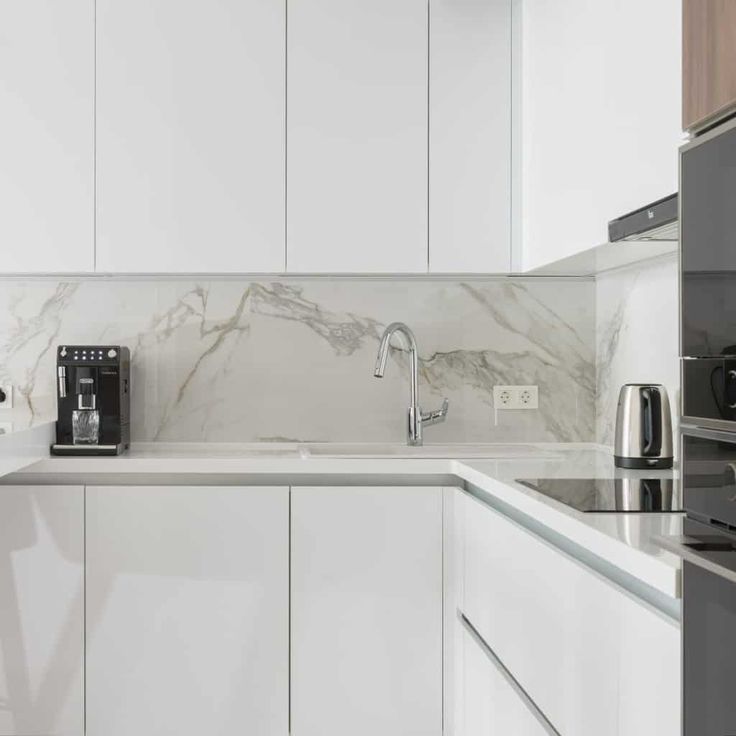 a kitchen with white cabinets and marble counter tops, along with an electric stove top oven