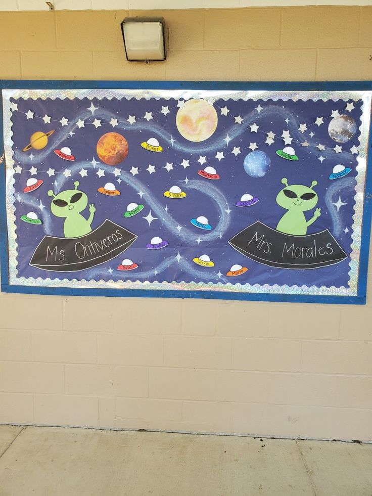 a space themed bulletin board hanging on the wall in a school hallway with an alien theme