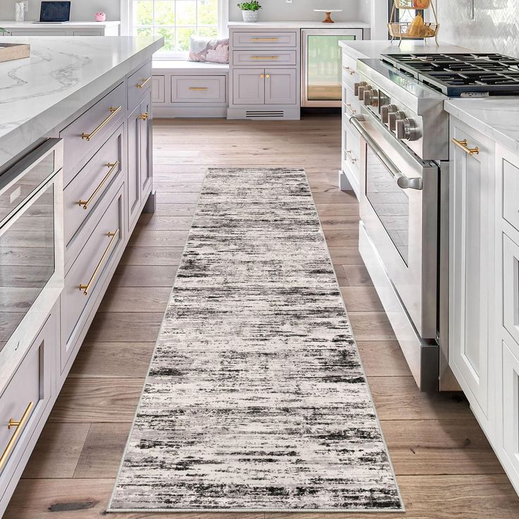 a kitchen with white cabinets and an area rug on the floor in front of the stove