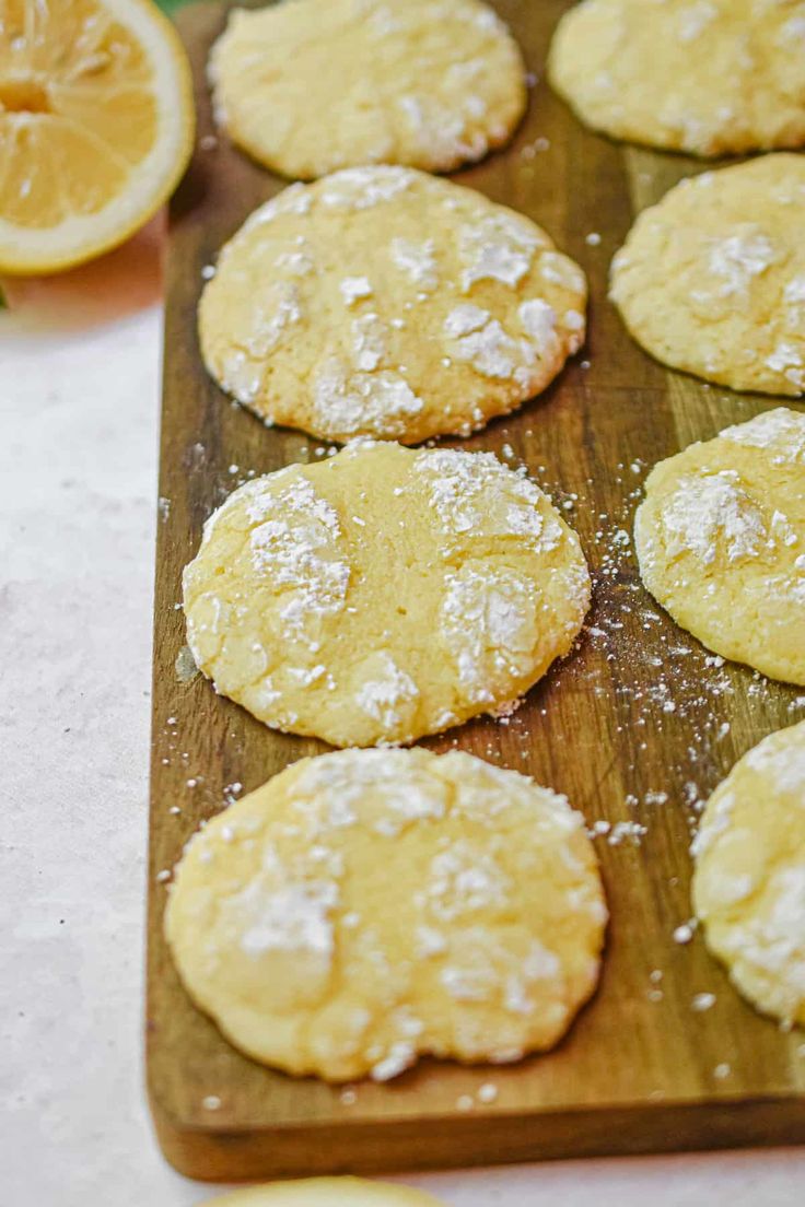 lemon cookies on a cutting board with powdered sugar and orange slices in the background