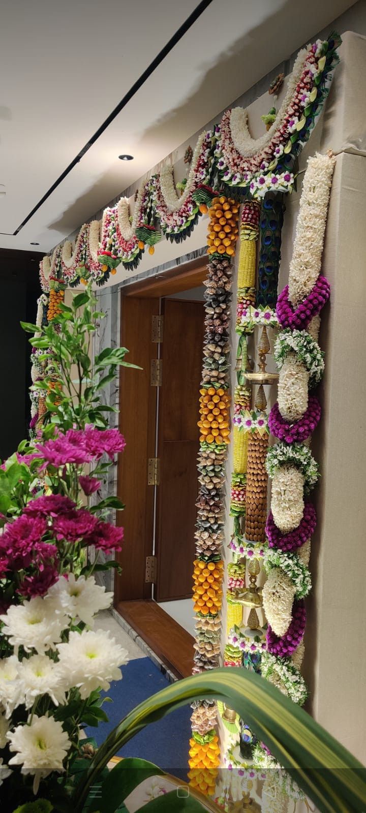 flowers are arranged on the wall in front of an entrance to a building that is decorated with garlands and beads