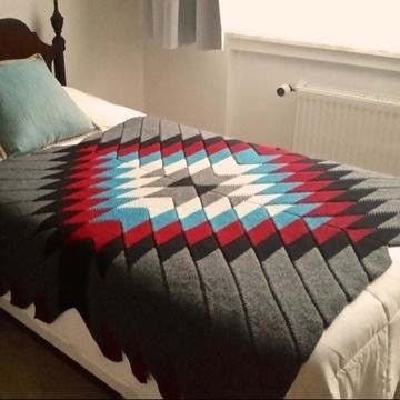 a bed with a blanket on top of it in a bedroom next to a window